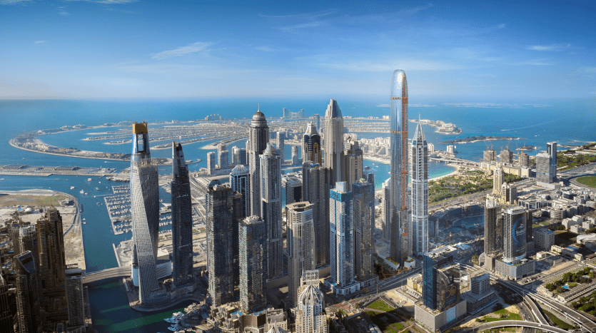 Vue aérienne d'une ville moderne avec des gratte-ciel imposants, des voies navigables côtières et des îles artificielles, sous un ciel bleu clair à Dubaï.