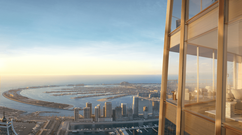 Vue depuis le balcon d'un immeuble de grande hauteur à Dubaï au coucher du soleil, surplombant un paysage urbain côtier avec des gratte-ciel et une rivière sinueuse menant à la mer.