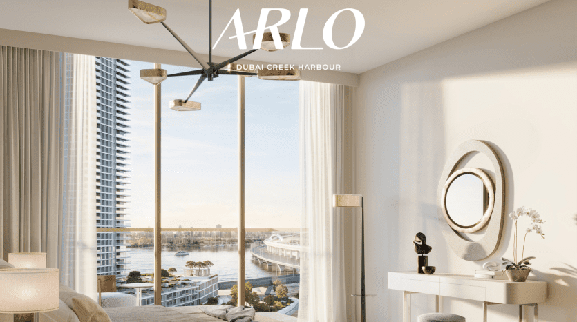 Une chambre sereine et moderne avec des baies vitrées donnant sur le front de mer du port de Dubai Creek près d'Emaar. La pièce dispose d'un lustre chic, d'un élégant miroir circulaire au-dessus d'une console blanche et d'un décor minimaliste pour une atmosphère tranquille. "ARLO" est écrit en haut.