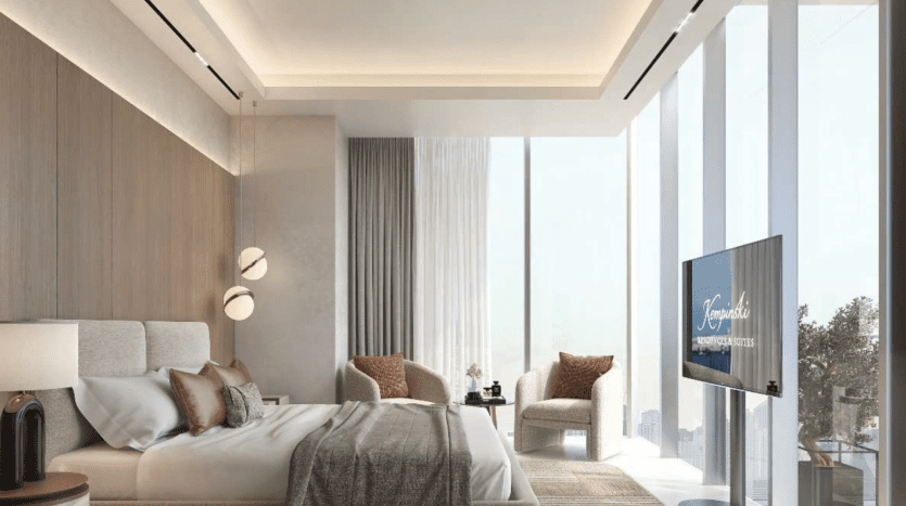 Chambre moderne dans un appartement de Dubaï avec de grandes fenêtres, un lit king-size, des panneaux en bois, des suspensions et une télévision murale. La pièce dégage une ambiance sobre et luxueuse avec une palette de couleurs neutres.