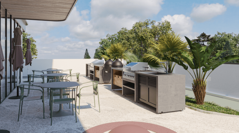 Le patio extérieur moderne du Primero Residences Al Furjan comprend plusieurs barbecues en métal et en béton, quelques tables rondes avec des chaises vertes et est entouré de verdure luxuriante et de palmiers. La zone est sous un ciel clair et ensoleillé, créant une atmosphère invitante pour cuisiner et manger en plein air.