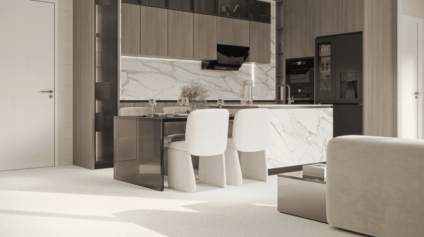 Une cuisine moderne au design épuré et minimaliste. Situé dans les résidences Primero Al Furjan, l'espace comprend des armoires beige clair, un dosseret en marbre, une table à manger avec quatre chaises rembourrées blanches et des appareils électroménagers intégrés. La conception globale met l’accent sur des tons neutres et des lignes épurées et contemporaines.