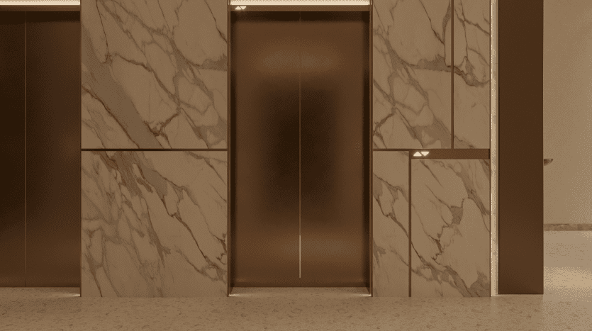 La section murale revêtue de marbre des Primero Residences Al Furjan présente un design minimaliste, avec deux portes d'ascenseur avec un éclairage subtil. Les ascenseurs sont encadrés dans une finition dorée, rehaussant l’aspect luxueux de la surface en marbre.
