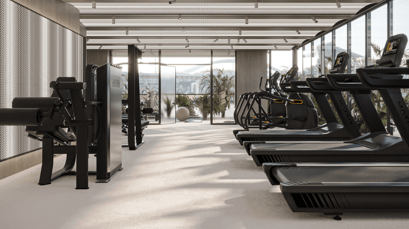Située au sein des Primero Residences Al Furjan, cette salle de sport moderne dispose de grandes fenêtres qui inondent l'espace de lumière naturelle. Doté de plusieurs tapis roulants, vélos d'exercice et autres équipements d'entraînement bien organisés, il offre un design épuré et minimaliste avec vue sur les plantes luxuriantes à l'extérieur.