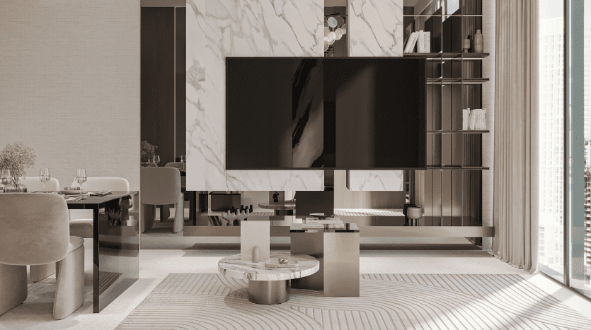 Le salon moderne du Primero Residences Al Furjan dispose d'une grande télévision à écran plat fixée sur un mur en marbre avec des étagères sur la droite. L'espace est décoré dans des tons neutres de beige, blanc et gris clair. Une table basse ronde et un canapé sectionnel sont judicieusement placés près du téléviseur.