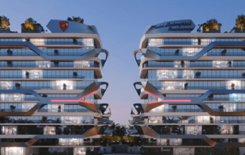 Deux bâtiments résidentiels modernes de plusieurs étages dotés de baies vitrées et de conceptions architecturales angulaires se côtoient, ornés de verdure sur leurs toits. Les deux bâtiments affichent bien en évidence sur leurs façades le label « Tonino Lamborghini Residences Dubai ». Le ciel est d'une teinte crépusculaire.