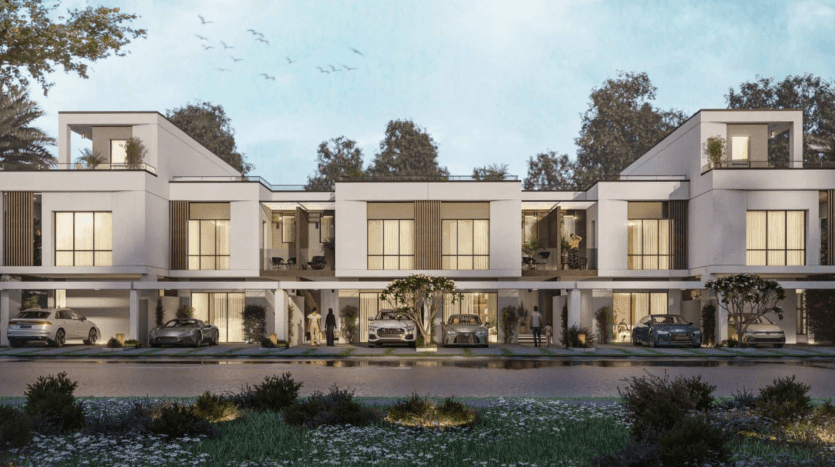 Un rendu numérique d'un complexe résidentiel moderne du sud de Dubaï comprenant des maisons de ville élégantes à deux étages avec des façades blanches, de vastes balcons et des abris de voiture intégrés, sur fond d'arbres et d'un ciel crépusculaire.