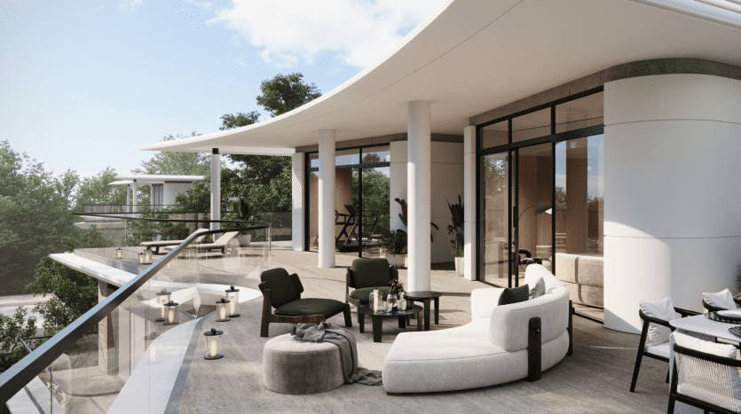 Patio extérieur moderne de la Villa Karl Lagerfeld doté d'un mobilier blanc élégant et de chaises vertes, installé sur une terrasse en bois avec des sièges rembourrés et des balustrades en verre élégantes, entouré d'une verdure luxuriante et
