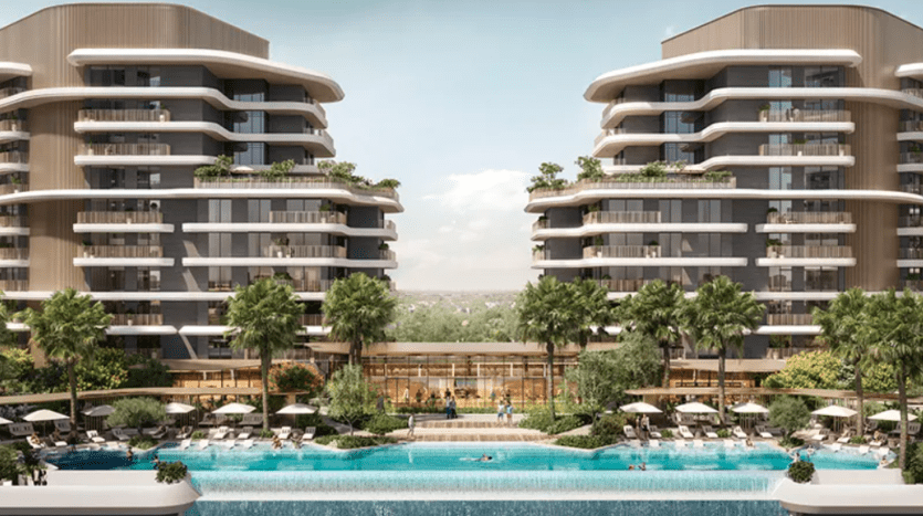 Verdes, un complexe résidentiel moderne, comprend deux bâtiments de plusieurs étages dotés de balcons incurvés, entourés d'une verdure luxuriante. Une vaste piscine extérieure, dotée de chaises longues et de palmiers, se trouve au premier plan, offrant une atmosphère luxueuse et relaxante.