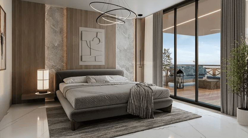 Une chambre moderne comprend un grand lit avec une literie grise et une couverture texturée. La pièce est décorée avec des œuvres d'art murales contemporaines, des luminaires minimalistes et de grandes baies vitrées qui s'ouvrent sur un balcon avec des sièges extérieurs et une vue panoramique.