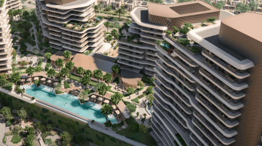 Vue aérienne d'un complexe résidentiel moderne comprenant plusieurs immeubles de grande hauteur dotés de balcons incurvés. La zone centrale, appelée Verdes Gardens, possède des arbres luxuriants et une grande piscine entourée de chaises longues. Les bâtiments présentent une conception architecturale contemporaine.
