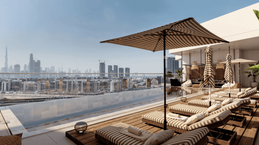 Une piscine luxueuse sur le toit des jardins Ayana avec des chaises longues rayées, de grands parasols et des gratte-ciel en arrière-plan. La terrasse au bord de la piscine offre de vastes vues urbaines sous un ciel bleu clair, avec des bâtiments modernes et une haute tour au loin.