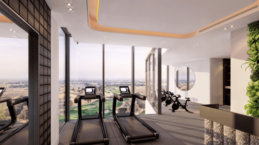Une salle de sport moderne dotée de baies vitrées offre une vue sur les vastes jardins Ayana. La salle dispose de tapis roulants, de vélos d'exercice et d'un design intérieur élégant avec des plantes et un éclairage contemporain.