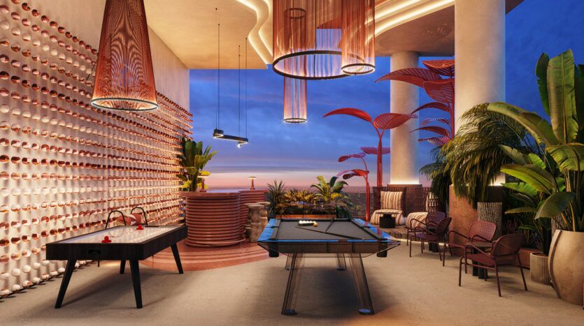 Une salle de loisirs élégante à Allura Residences avec une décoration moderne au coucher du soleil. Elle comprend une table de billard, une table de air hockey, des sièges haut de gamme et une installation murale avec des éléments ronds. De grandes plantes et des plafonniers uniques rehaussent l'ambiance. Une vue imprenable est visible à l'extérieur.