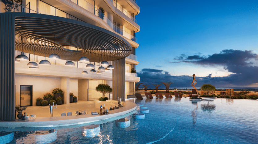 La luxueuse piscine à débordement sur le toit au coucher du soleil, conçue par Allura Citi Developers, est entourée d'une architecture moderne. Un éclairage ambiant sous un auvent circulaire complète le bar de la piscine avec des boissons et des chaises longues avec parasols. Une statue saisissante orne une île dans l'eau.