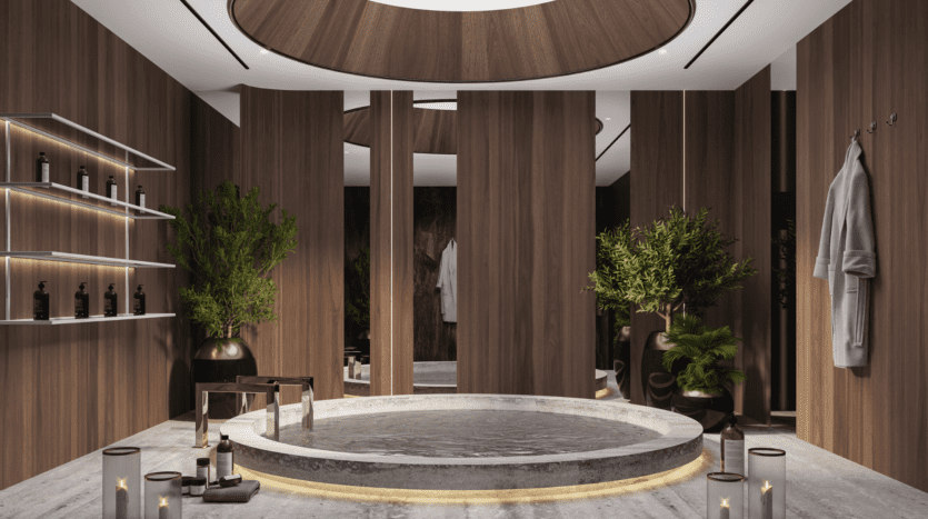 La salle de spa moderne et luxueuse du One Beverly Dubai dispose d'une baignoire ronde encastrée entourée de bougies. Les murs en bois ajoutent de la chaleur, tandis que les étagères accueillent les produits de toilette. Des plantes en pot et un peignoir suspendu renforcent l'ambiance sereine.