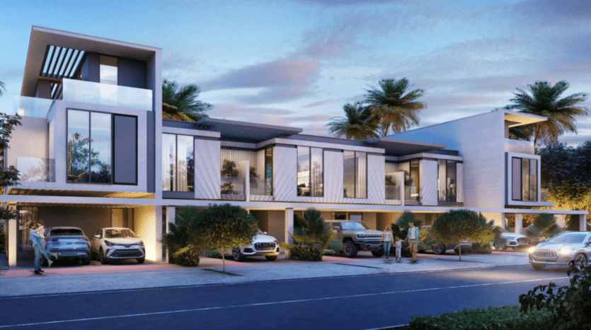 Un complexe de maisons de ville moderne à deux niveaux avec de grandes fenêtres, rappelant une villa Damac, avec plusieurs voitures garées devant. Des palmiers et de la verdure bordent la zone. La scène se déroule le soir avec un ciel coloré de Sun City en arrière-plan.