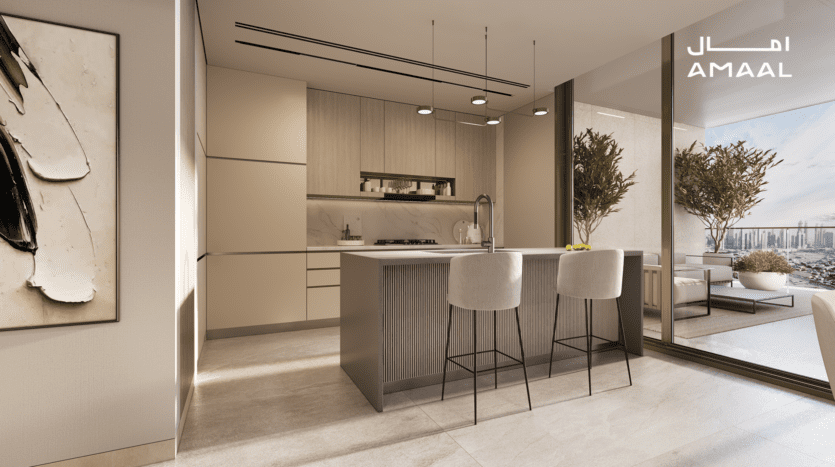 Intérieur de cuisine moderne avec îlot central avec tabourets de bar, armoires élégantes et éclairage suspendu. Grâce à des portes coulissantes en verre, un balcon avec vue sur la ville et des plantes en pot ajoute du charme au design de l'Amaal 8. Des œuvres d'art minimalistes décorent le mur.