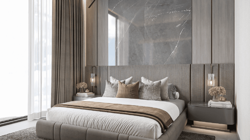 Une chambre moderne au One Park Square dispose d'un grand lit rembourré orné d'oreillers assortis et d'une couverture marron. Les murs en marbre et les luminaires suspendus rehaussent son élégance, tandis que les fenêtres du sol au plafond avec des rideaux transparents invitent une lumière naturelle abondante.