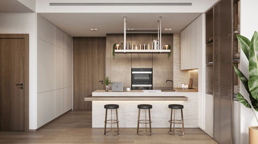 The Highgrove kitchen features a marble island with three black stools and sleek wooden cabinets. A laptop and small plants adorn the countertop, while above, a shelf filled with books complements the built-in oven. Wooden flooring enhances the room's warmth, complemented by a large green plant in the corner.