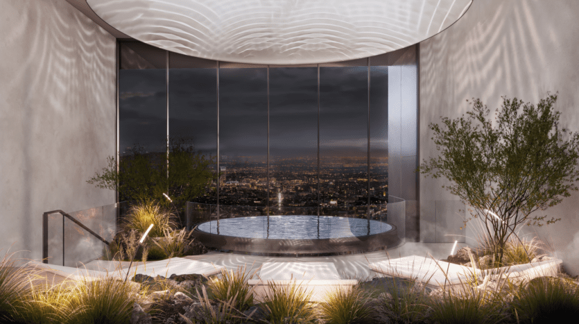 A luxurious indoor pool with city lights visible through large picture windows at night. The space is tastefully decorated with plants, rocks and soft lighting, creating an elegant, serene atmosphere.