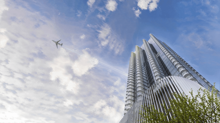 Un gratte-ciel moderne aux formes cylindriques uniques se dresse à côté des emblématiques W Residences, sur fond de ciel partiellement nuageux. Un avion à réaction vole à proximité, laissant une traînée de condensation dans son sillage. La cime d'un arbre vert est visible dans le coin inférieur droit.