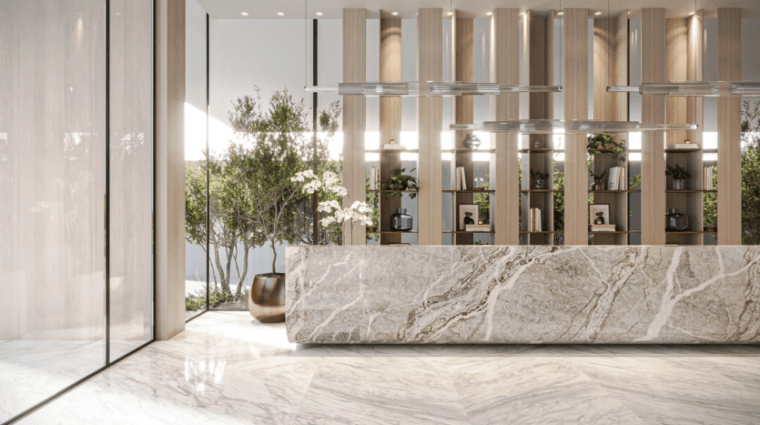 Le hall d'entrée moderne de l'hôtel Legado Prescott est doté d'un comptoir de réception en marbre, d'étagères en bois et de plantes décoratives. La lumière naturelle pénètre à travers de grandes fenêtres, mettant en valeur le design minimaliste et la décoration élégante.