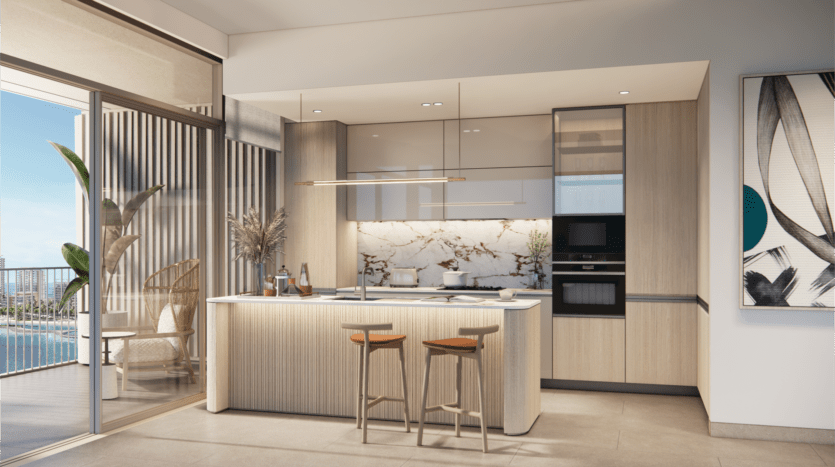 Découvrez la cuisine moderne du Bay Grove Residences, dotée d'un îlot en marbre, de deux tabourets de bar en bois et d'appareils électroménagers intégrés. De grandes portes vitrées s'ouvrent sur un patio avec vue sur la ville et la piscine. Un tableau orne le mur de droite, tandis que des plantes en pot ajoutent de la verdure à cet espace épuré aux tons neutres.