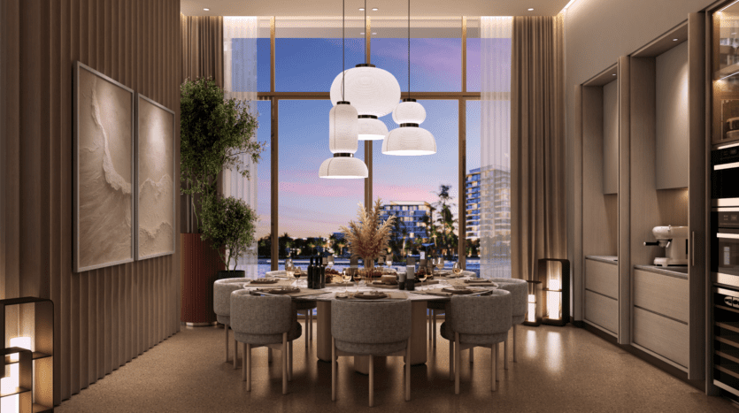 Une salle à manger moderne dans les résidences Bay Grove comprend une table ronde dressée pour un repas, entourée de chaises rembourrées. De grandes suspensions sont suspendues au-dessus. Les baies vitrées offrent une vue sur le paysage urbain au crépuscule. La décoration comprend des œuvres d'art, des plantes et un éclairage d'ambiance.