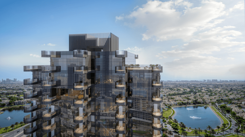Un gratte-ciel moderne, faisant partie des résidences W, est doté de vitres réfléchissantes et de balcons sur fond de paysage urbain. Le ciel est partiellement nuageux, complétant un plan d'eau proéminent entouré de verdure au premier plan.