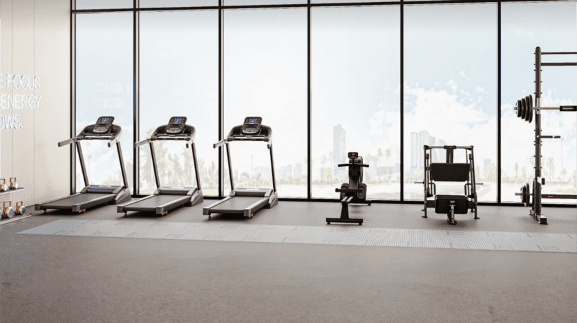 La salle de sport Cove Edition 2 est dotée de grandes fenêtres qui dévoilent l'horizon de la ville. Dotée de trois tapis de course, d'un rameur et d'un support de poids, elle est lumineuse et spacieuse. La lumière naturelle met en valeur le design moderne et minimaliste qui est essentiel à l'expérience Cove Edition 2.