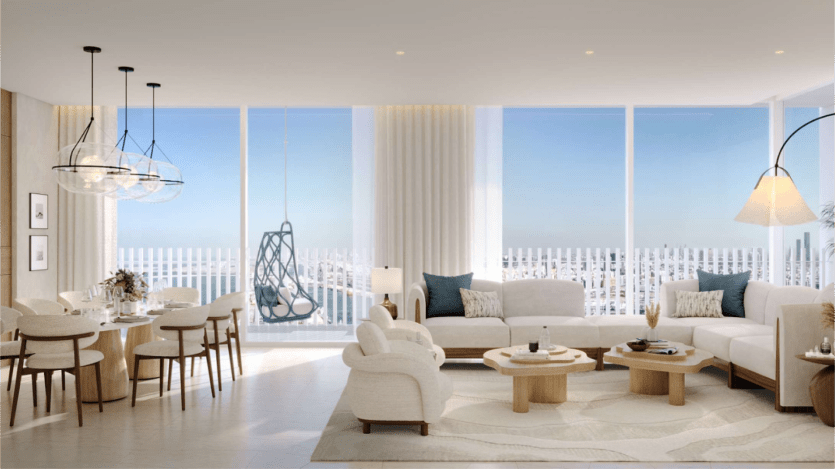 Un salon et une salle à manger modernes avec des baies vitrées offrant une vue sur le paysage urbain de Saria. Il est doté de meubles de couleur neutre, notamment des canapés, un ensemble de salle à manger, une chaise suspendue et un éclairage décoratif, créant un espace lumineux et ouvert.