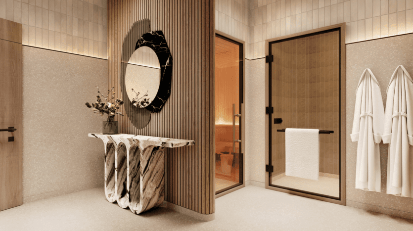 Salle de bains luxueuse au design moderne au W Residences. Un lavabo en marbre unique est associé à un grand miroir artistique. Une porte vitrée mène à un sauna et deux peignoirs blancs sont accrochés au mur. L'espace, inspiré des Jumeirah Lake Towers, est élégamment éclairé et doté de boiseries claires.