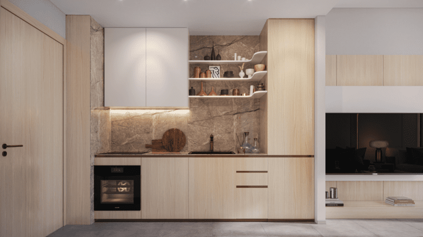 Cuisine moderne avec armoires en bois clair, four encastré et étagères ouvertes. Dosseret en pierre avec éclairage d'appoint mettant en valeur les objets décoratifs. Le design Legado Prescott reflète un style minimaliste avec des tons neutres et des finitions épurées. Espace de vie adjacent partiellement visible.