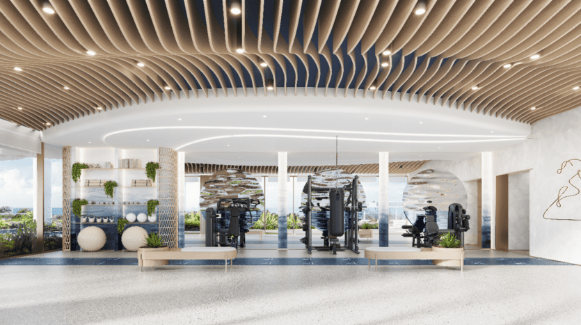 Une salle de sport moderne et spacieuse à Sunset Bay avec des accents de plafond en bois, de grands miroirs, des appareils d'exercice et des ballons de fitness. Les baies vitrées révèlent une vue panoramique sur l'extérieur. Des plantes décoratives rehaussent l'atmosphère aérée et accueillante.