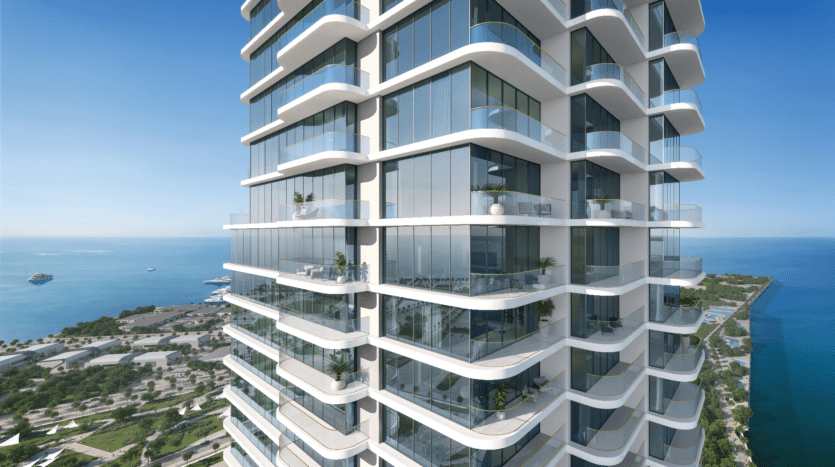 Le LIV Maritime, un immeuble d'appartements moderne de grande hauteur avec des balcons incurvés et des façades en verre, surplombe un paysage côtier. L'océan et un parc avec de la verdure sont visibles en arrière-plan sous un ciel bleu clair.