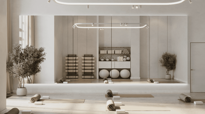 LIV Maritime présente un studio de yoga minimaliste, où tapis, traversins et blocs enroulés sont soigneusement disposés sur le sol. Des étagères à l'arrière accueillent des tapis supplémentaires et des ballons d'exercice. De grandes fenêtres et des plantes renforcent l'atmosphère maritime sereine.