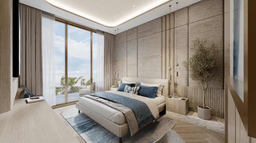 La chambre moderne du Sunset Bay dispose d'un grand lit avec une literie bleue et blanche. Elle est ornée d'un mur d'accent en bois, d'une plante en pot et de baies vitrées s'ouvrant sur un balcon donnant sur la mer et les palmiers. Un éclairage doux renforce l'ambiance chaleureuse.