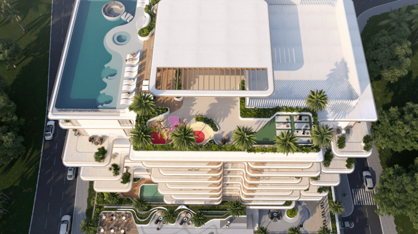 Vue aérienne du bâtiment moderne à plusieurs étages de Sunset Bay avec piscines sur le toit, végétation luxuriante et espaces de loisirs variés. La structure comprend des balcons incurvés, un aménagement paysager artistique et des espaces de repos extérieurs, le tout élégamment entouré de palmiers pour une évasion sereine.