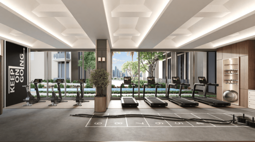 Le Hillgate dispose d'une salle de sport moderne avec des tapis roulants face à des baies vitrées donnant sur un paysage urbain et des espaces verts. La salle comprend des vélos d'exercice, un panneau de motivation « KEEP GOING », un motif de marelle sur le sol, des cordes et des équipements de fitness.