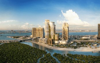 Vue aérienne de Rivage, un paysage urbain côtier présentant des immeubles modernes de grande hauteur au bord d'un cours d'eau et des mangroves verdoyantes. L'horizon sous un ciel bleu clair met en valeur le mélange harmonieux du développement urbain et du paysage naturel.