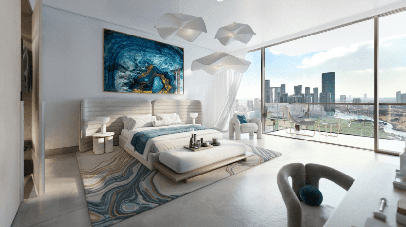 Chambre moderne avec un grand lit, une œuvre d'art abstraite au-dessus et des suspensions géométriques. Une baie vitrée offre une vue sur le paysage urbain de Rivage avec ses gratte-ciels. La chambre présente une palette de couleurs blanche et bleue et un balcon avec des sièges.