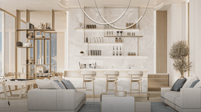 Un salon moderne avec les canapés Cove Edition 3 de couleur claire, une table basse et une cuisine en marbre en arrière-plan. L'espace comprend des étagères ouvertes avec des objets de décoration, un luminaire incurvé et de grandes fenêtres baignant la pièce de lumière naturelle.
