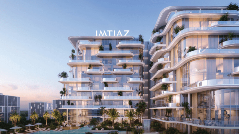 Le bâtiment moderne Cotier House présente des immeubles d'appartements luxueux aux façades vitrées et aux balcons arrondis, enveloppés d'une végétation luxuriante. Une piscine étincelante orne le premier plan, tandis que le ciel bleu clair complète cette scène sereine.