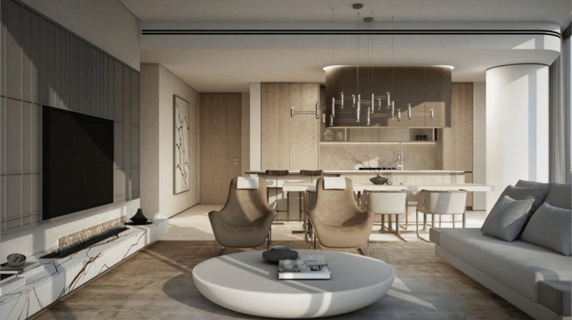 Un salon moderne avec une grande télévision, deux fauteuils et un canapé gris jouxte la cuisine ouverte. L'espace dispose d'une table basse ronde et d'un lustre élégant sur des surfaces en marbre. La lumière naturelle pénètre à travers de grandes fenêtres, mettant en valeur cette maison de rêve de propriétés SaaS.