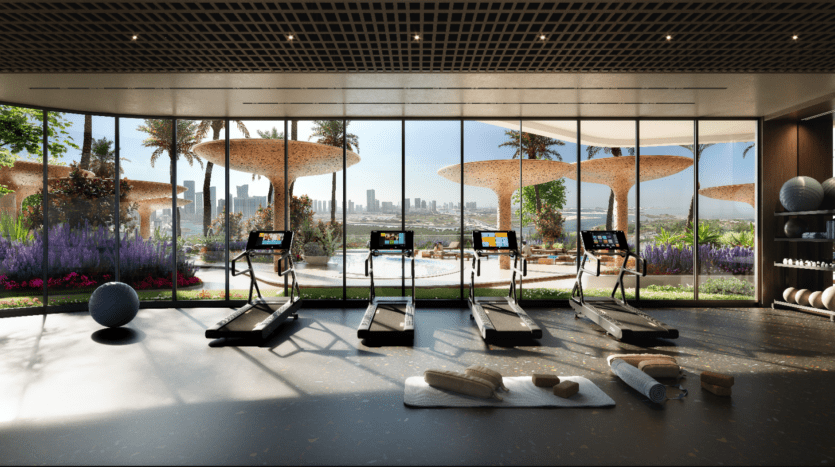 Une salle de sport moderne, Rivage, dispose de quatre tapis de course faisant face à de grandes fenêtres avec une vue imprenable sur les toits de la ville. À l'extérieur, des structures en forme de champignon se nichent dans une végétation luxuriante. Un tapis de yoga avec des serviettes pliées et un ballon d'exercice reposent sur le sol, complétant ce havre de remise en forme serein.