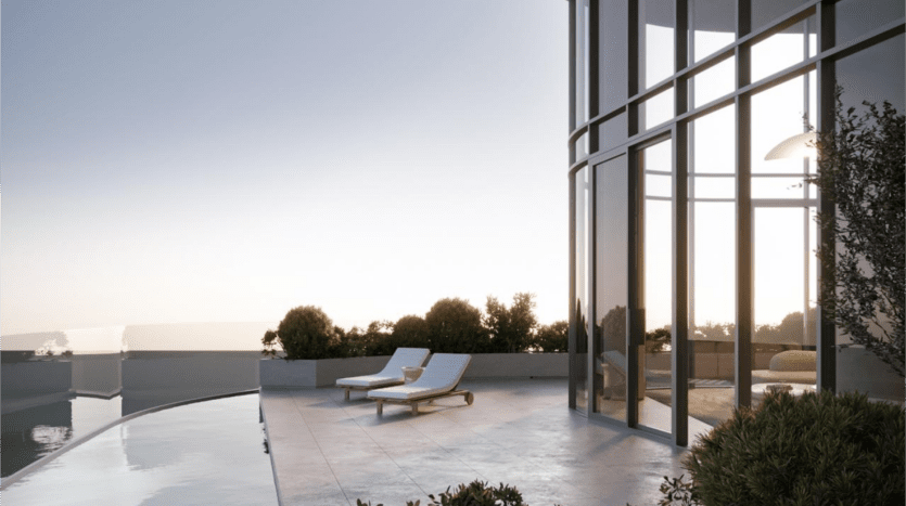 La terrasse moderne sur le toit de SaaS Properties est dotée d'une balustrade en verre incurvée offrant une vue panoramique. Deux chaises longues font face à l'horizon à côté d'une piscine réfléchissante. La scène est sereine, avec une douce lumière du soleil filtrant à travers de grandes fenêtres en verre et de la verdure entourant l'espace.