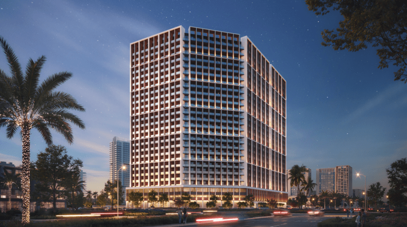 Un immeuble de bureaux moderne à plusieurs étages de Binghatti ELITE la nuit, illuminé par des lumières. Des palmiers bordent la rue en face et le ciel est rempli d'étoiles. Des voitures avec des traînées lumineuses se déplacent le long de la route, ajoutant à la scène animée.