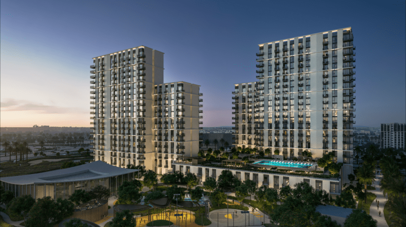 Une vue nocturne du complexe d'appartements Hillsedge révèle deux hauts bâtiments ornés de nombreux balcons. Ils entourent une cour centrale présentant une piscine éclairée et des jardins bien entretenus, tandis que le ciel passe élégamment du crépuscule à l'obscurité.