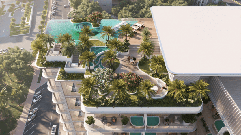 Vue aérienne d'un bâtiment moderne, Cove Edition 4, doté de jardins luxuriants sur le toit et d'une piscine incurvée. Des palmiers, des plantes et des coins salons créent une ambiance tropicale. Les rues adjacentes et la verdure environnante sont visibles.